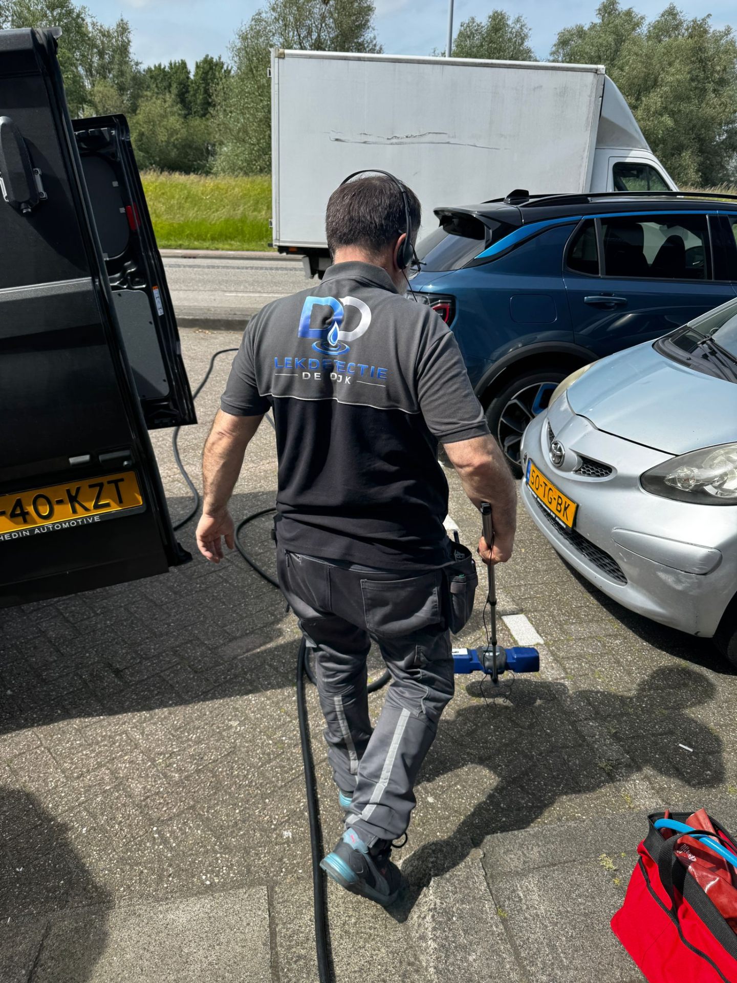 Monteur Lekdetectie De Dijk met akoestische meetapparatuur naast bedrijfsbus