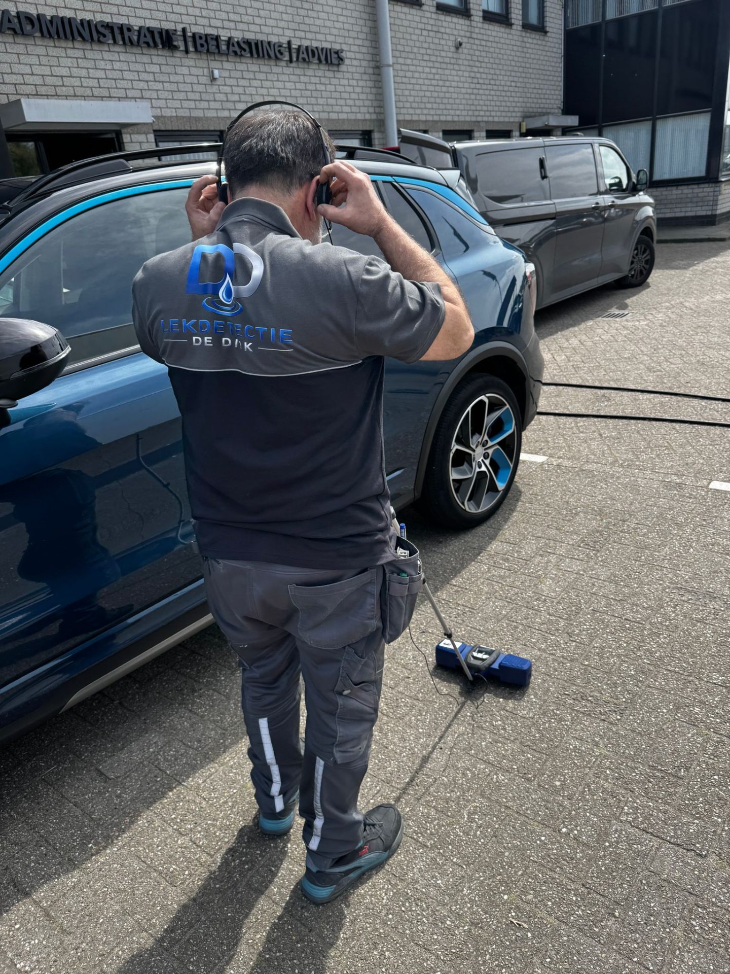 Specialist voert akoestische lekdetectie uit met koptelefoon op straat