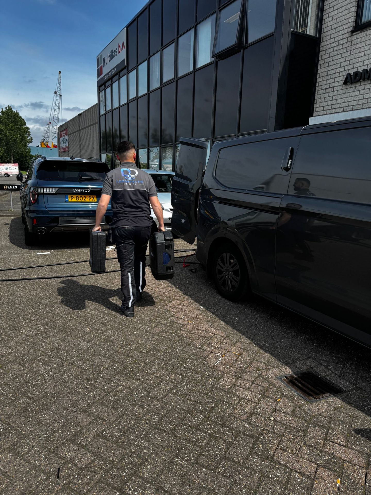Monteur laadt meetapparatuur uit bedrijfsbus voor lekdetectie op locatie